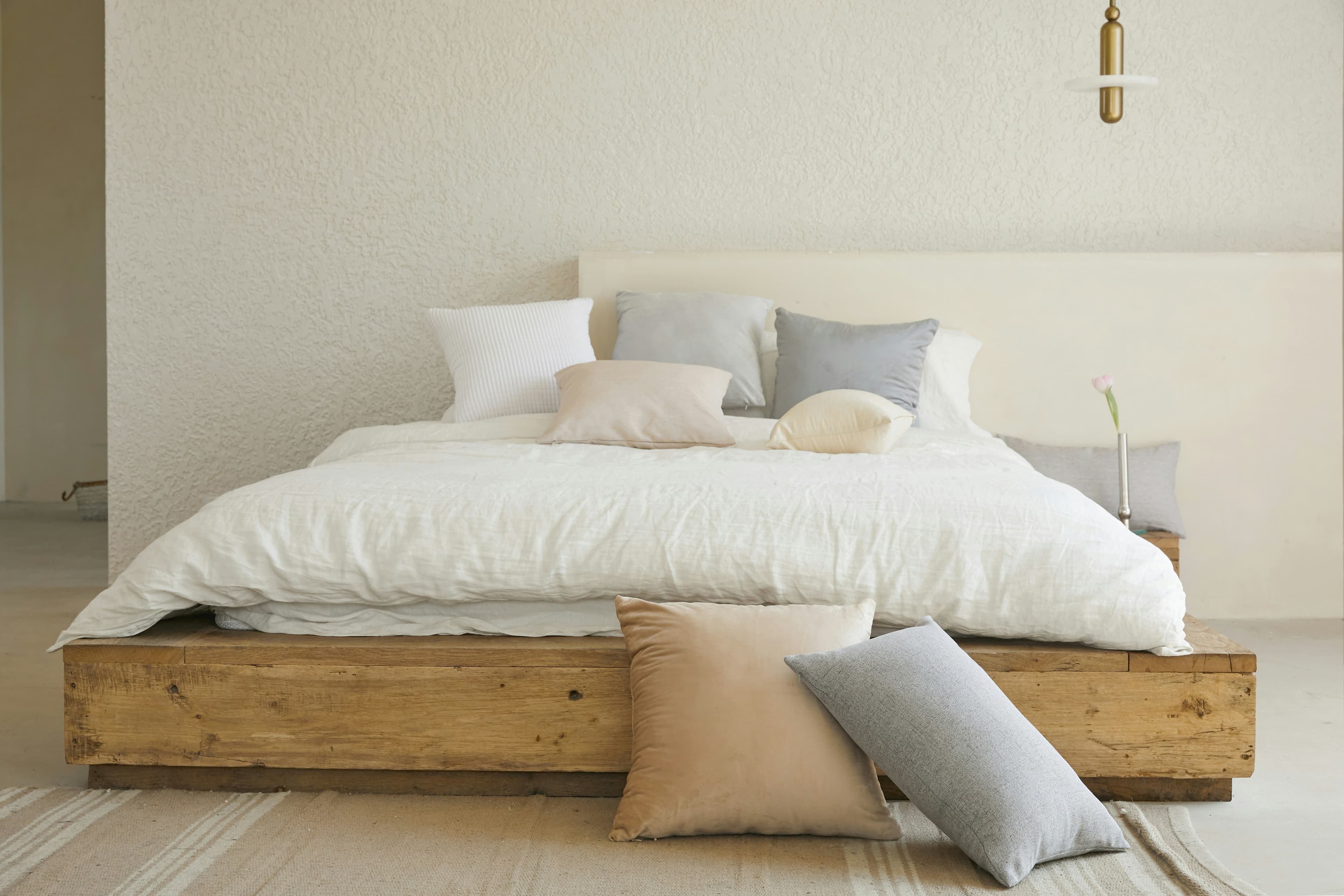 Recámara con cama de base baja en madera maciza y ropa de cama en tonos claros